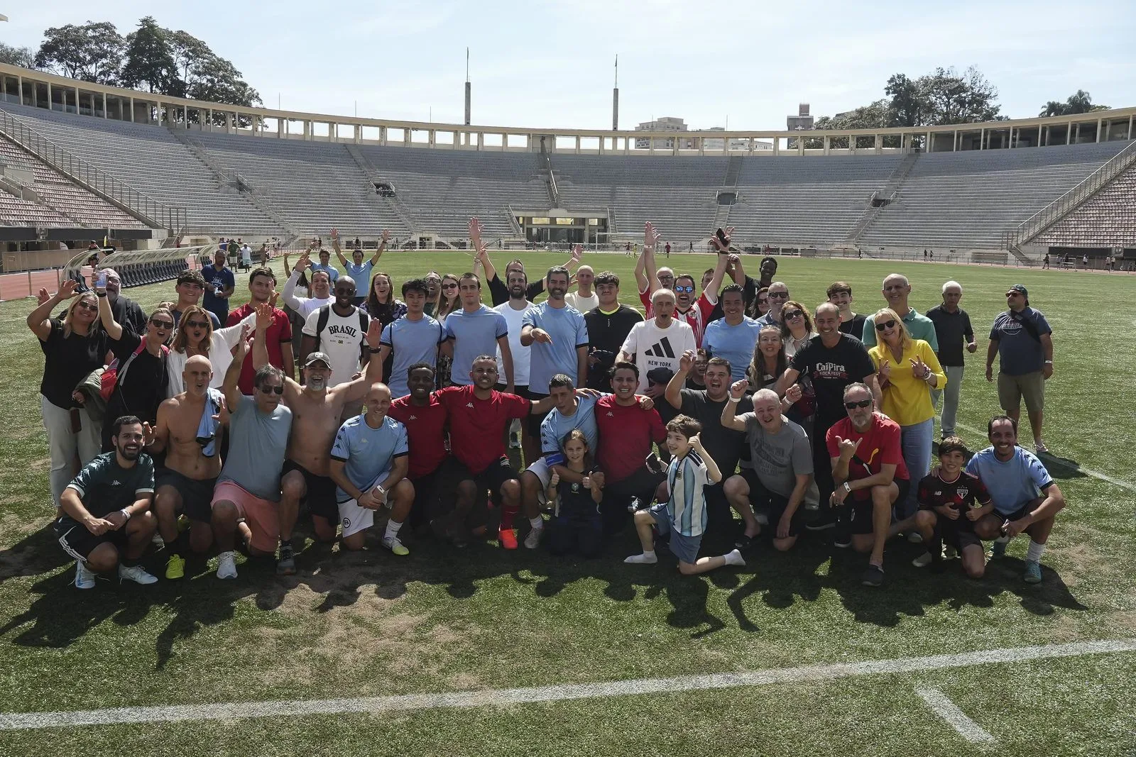 Participantes de um evento Confra FC comemorando no gramado de um estádio